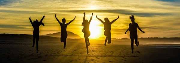 Sihlouttes of happy people jumping in the sunset