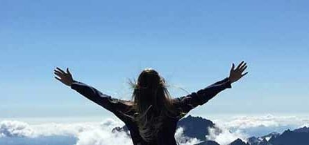 Woman raising her arm in triumph on mountain top