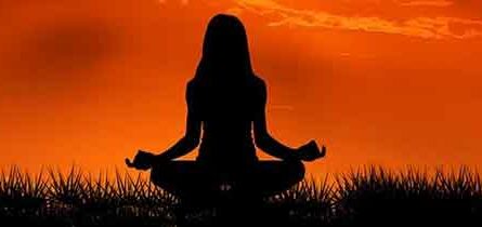 Does Your Back Have to be Straight When Meditating- Woman meditating in front of red sun set