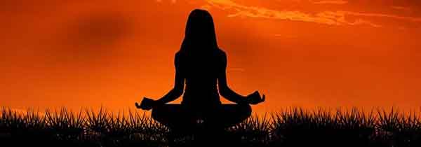 Does Your Back Have to be Straight When Meditating- Woman meditating in front of red sun set