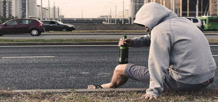 Does Alcohol lower Your Vibration-man-sitting-on-sidewalk-drinking-alone