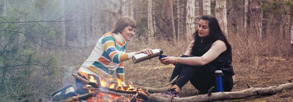 How Can I Help Someone Raise Their Vibration- Two women talking by a camp fire